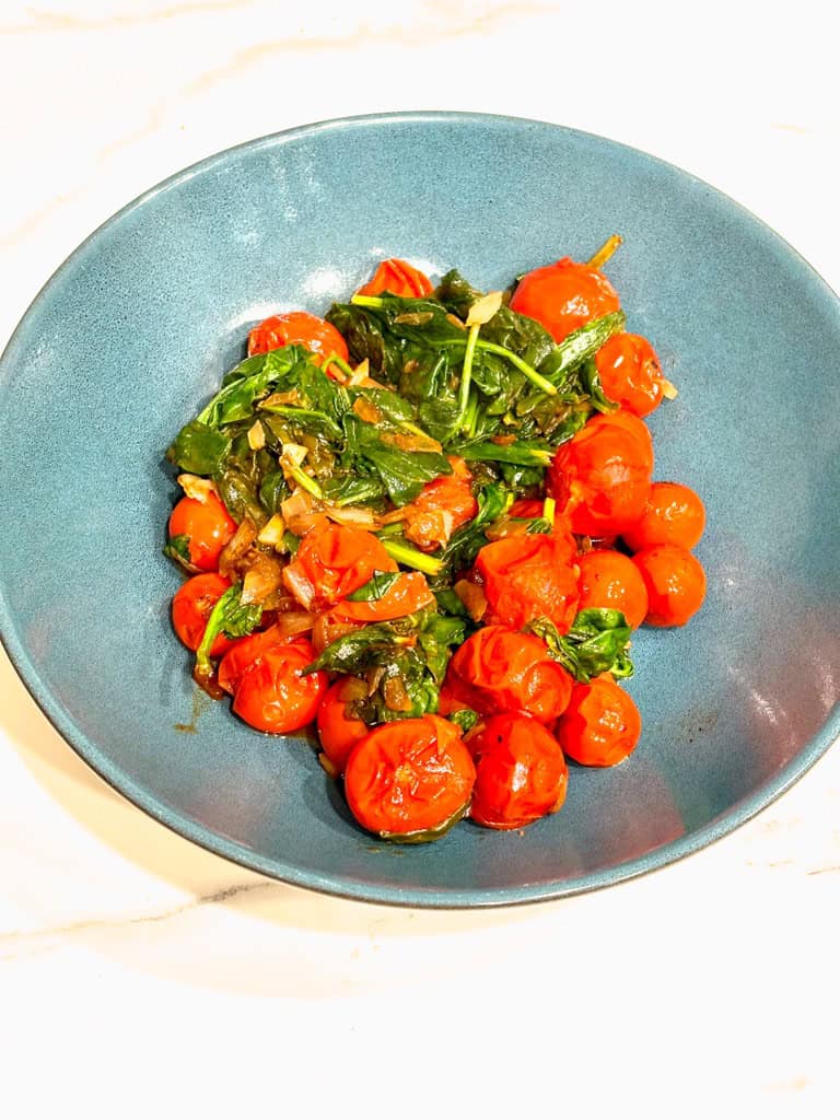 tomato and spinach saute in blue serving bowl