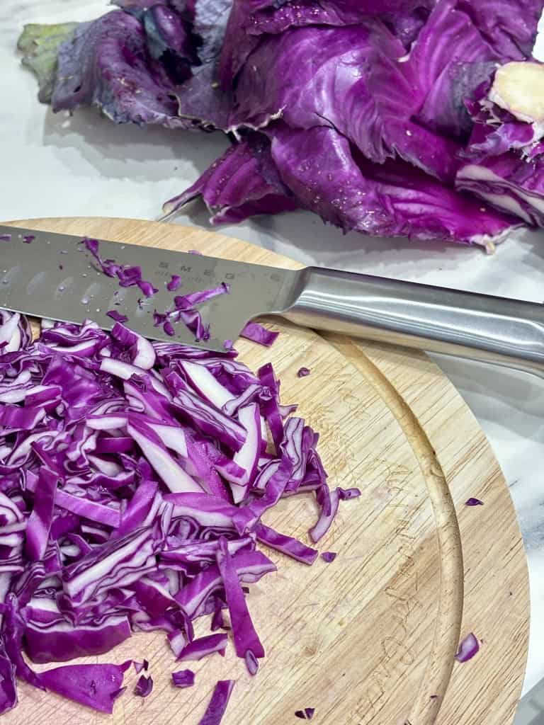 Chopped red cabbage on wooden cutting board with silver kitchen knife