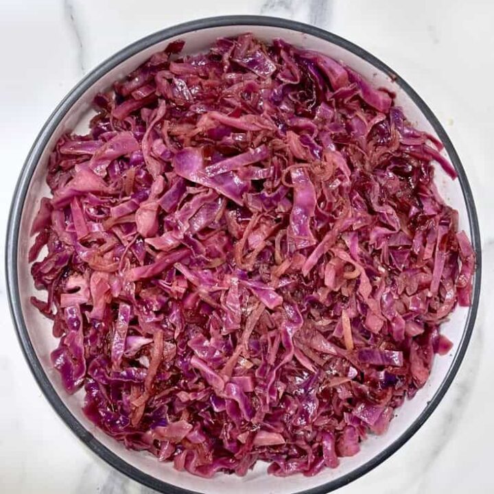 Braised red cabbage and apple in white serving bowl with black rim