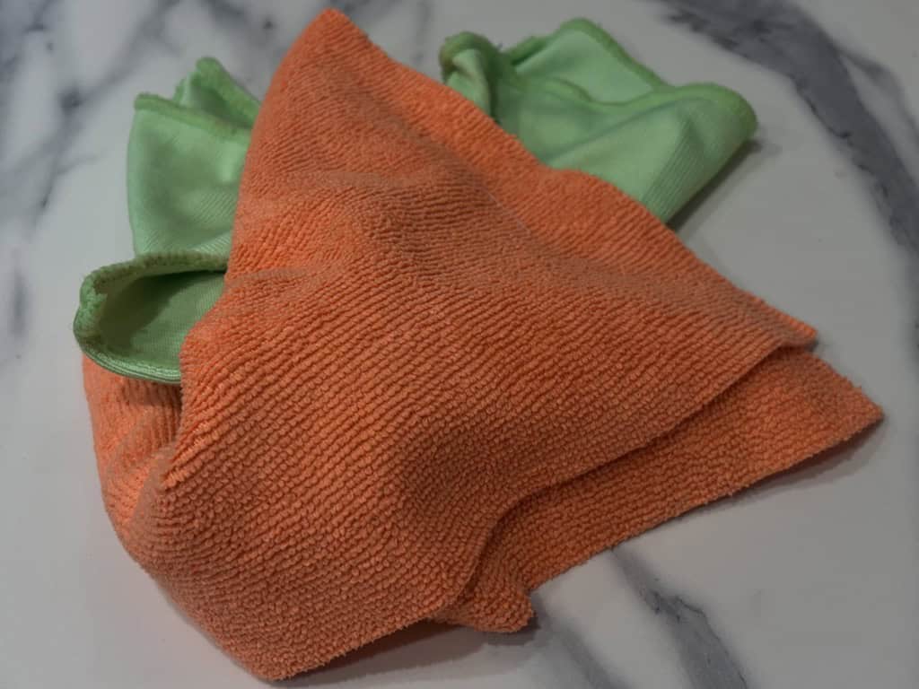 Orange and green microfibre cloths on marble surface