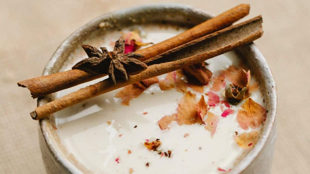 Close up shot of ceramic mug filled with hot milk, topped with spices