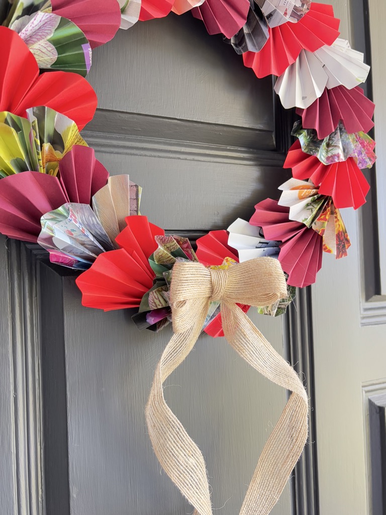 close up shot of red paper heart wreath on grey door