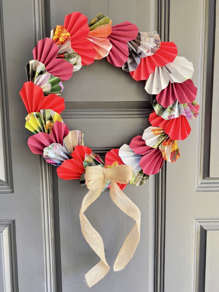 red paper heart wreath on grey door, decorated with bow