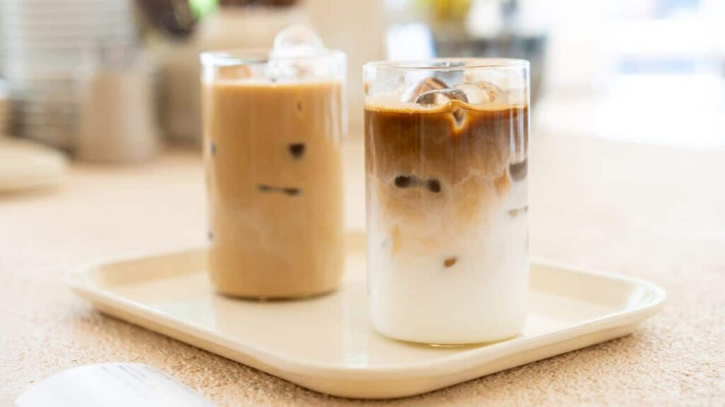 Two iced coffees in tall glasses on white tray