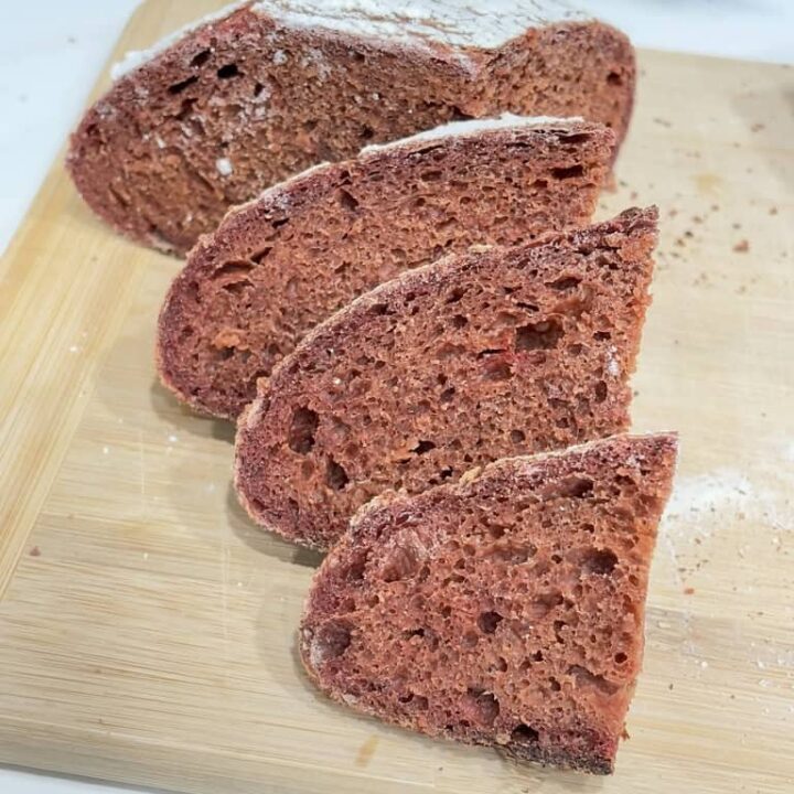 Slices of pink bread leaning on quarter loaf on wooden board