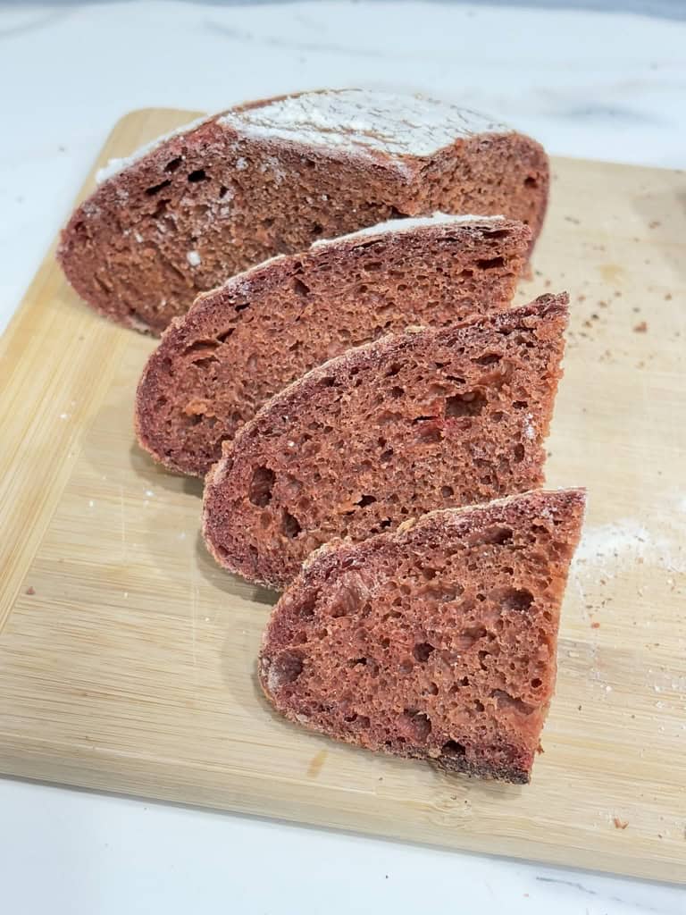 Slices of pink bread leaning on quarter loaf on wooden board