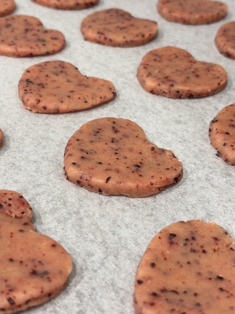 Heart shaped pink cookies on parchment paper