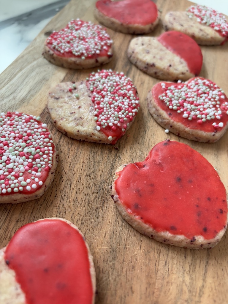 Red heart cookies on wooden cutting board