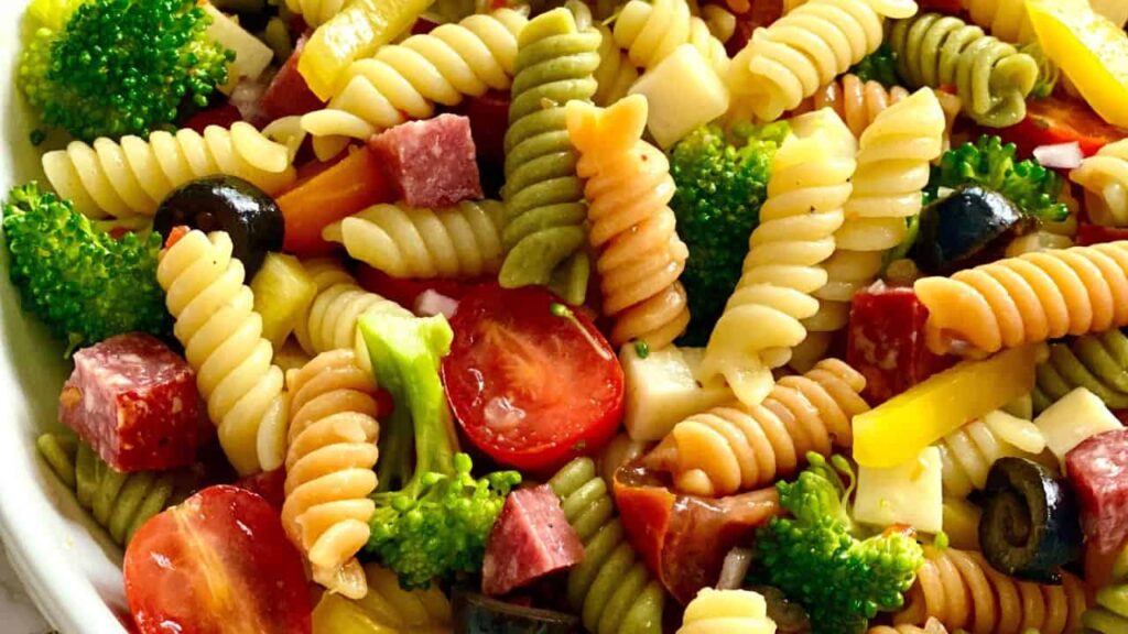 Close up shot of pasta salad with tomatoes, broccoli and pieces of sausage