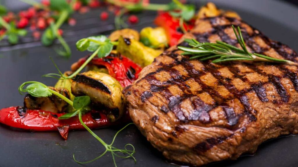 Grilled steak and grilled vegetables on black plate