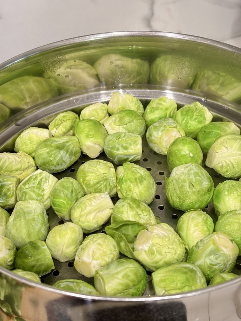 Metal colander filled with single layer of raw Brussels sprouts