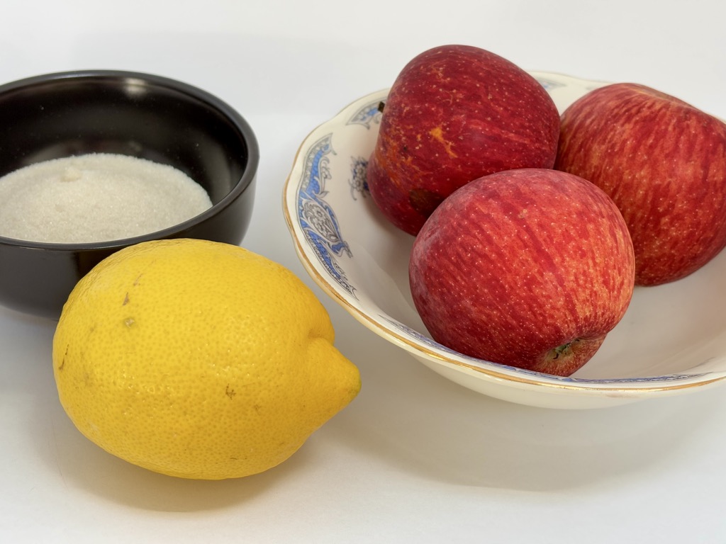 Bowl of red apples, bowl of sugar, and single lemon