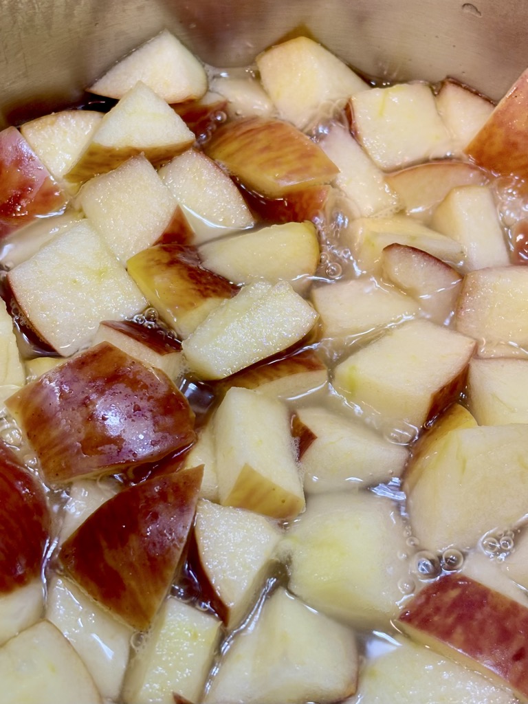 Chunks of red apples being simmered in water