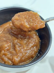 Silver spoon lifting applesauce out of black bowl