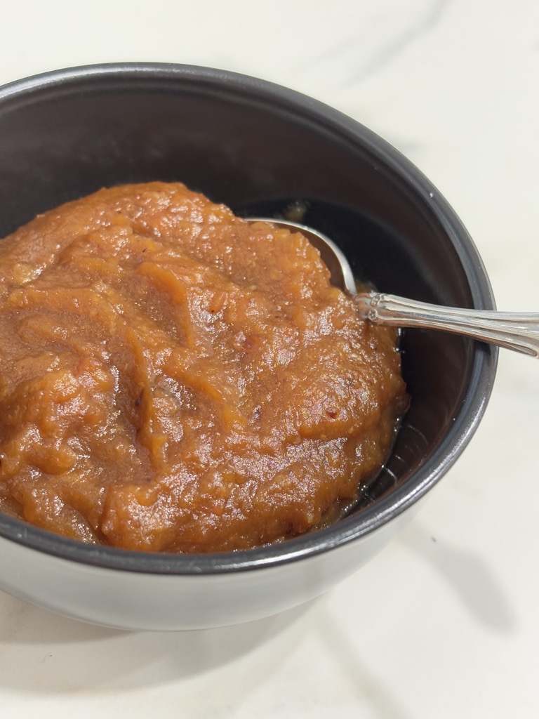 Caramelised applesauce in black bowl with silver spoon