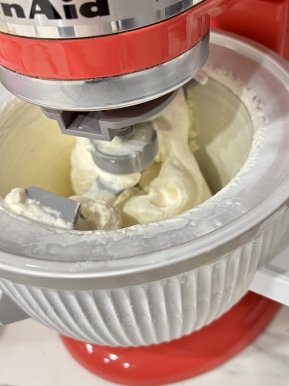 Stand mixer with ice cream attachment, filled with vanilla ice cream