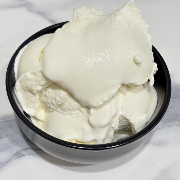 Egg free vanilla ice cream in black bowl on marble surface