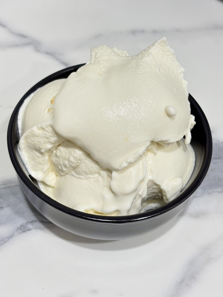 Egg free vanilla ice cream in black bowl on marble surface