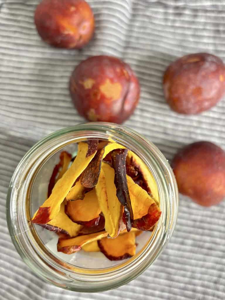 Top down shot of dehydrated plum slices on striped linen cloth filled with whole plums