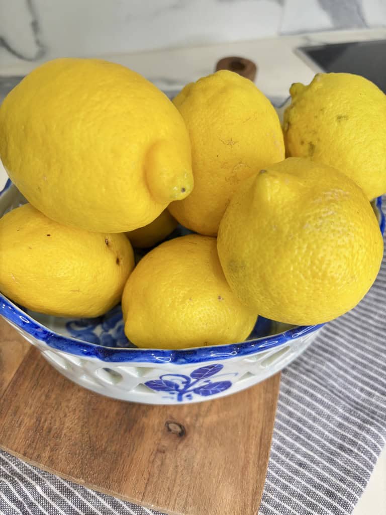 White and blue bowl on wooden board, filled with lemons