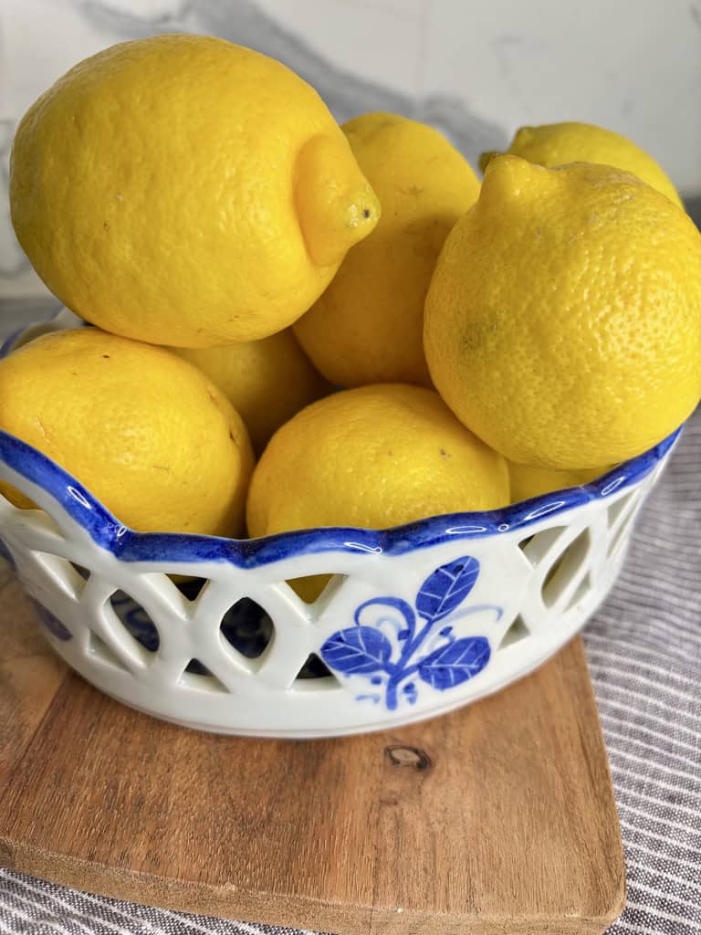 White and blue bowl on wooden board, filled with lemons