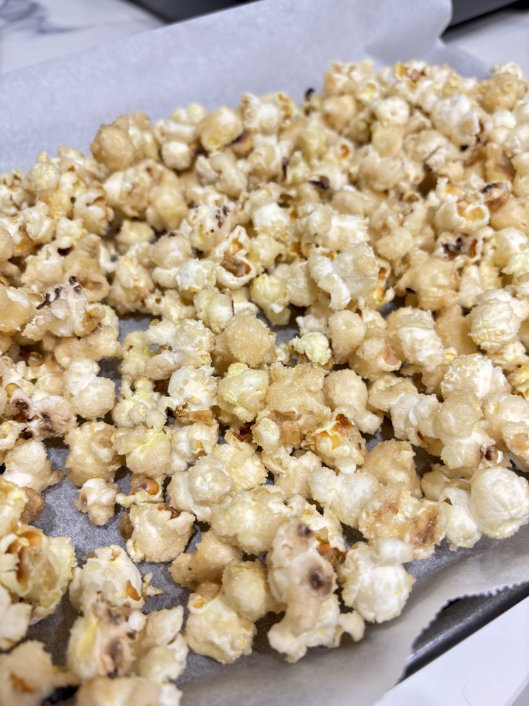 Vegan caramel popcorn on baking sheet lined with white parchment paper