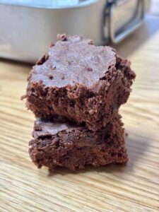 Two brownies stacked on wooden table