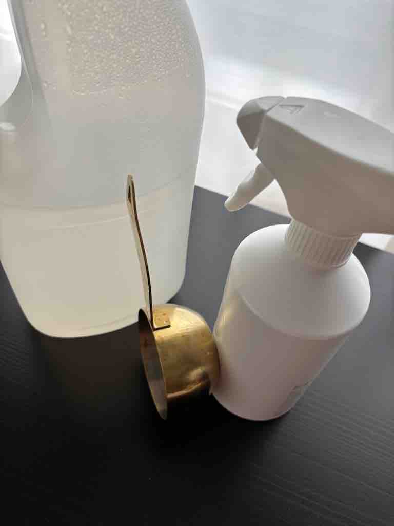 Homemade all-purpose cleaner setup with a gold measuring cup, spray bottle, and vinegar solution—perfect for natural, zero-waste cleaning routines.