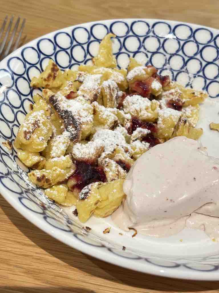 Crispy Kaiserschmarrn topped with berry compote and served with a scoop of ice cream – a traditional Austrian dessert.