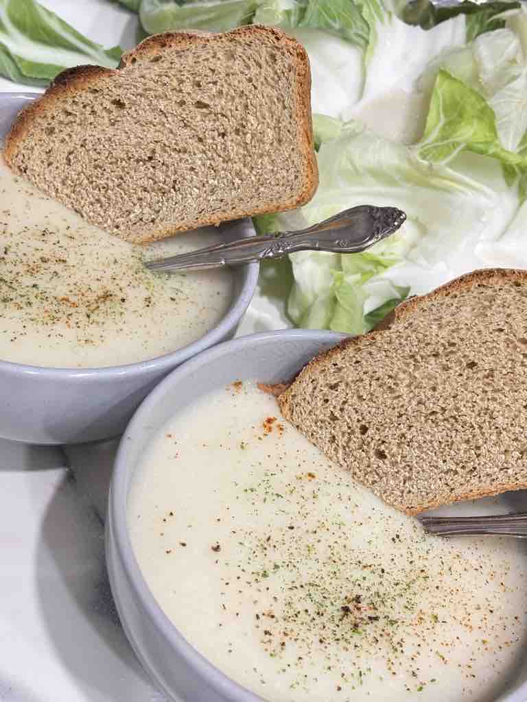 Rustic wholemeal bread resting on creamy cauliflower soup – a hearty and comforting vegetarian meal.