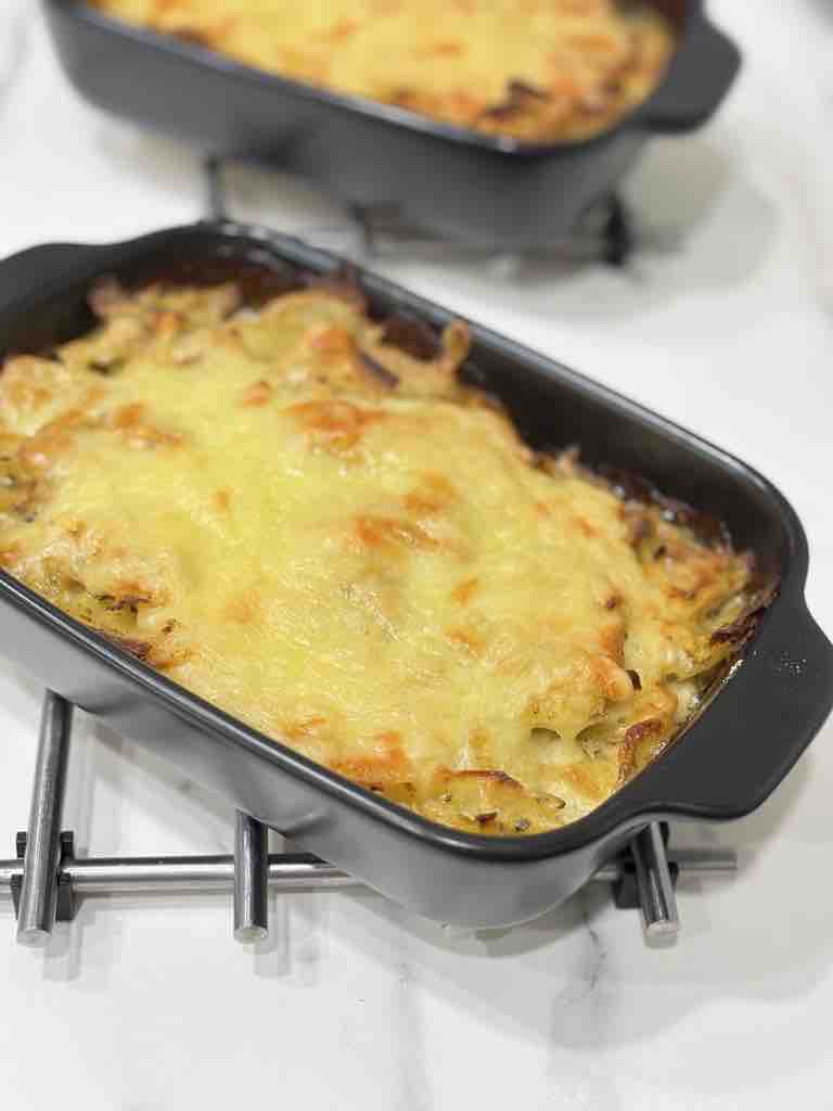 Two baking trays filled with perfectly baked potato gratin, topped with melted, golden-brown cheese and slightly crispy corners—comfort food heaven.