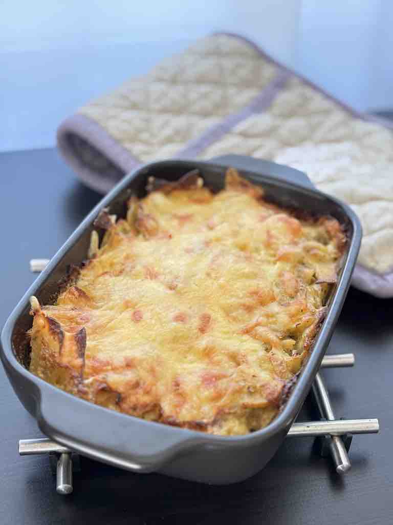 A rich and gooey potato gratin shown close up, fresh from the oven with cheese bubbling and golden around the edges—pure comfort in a tray.