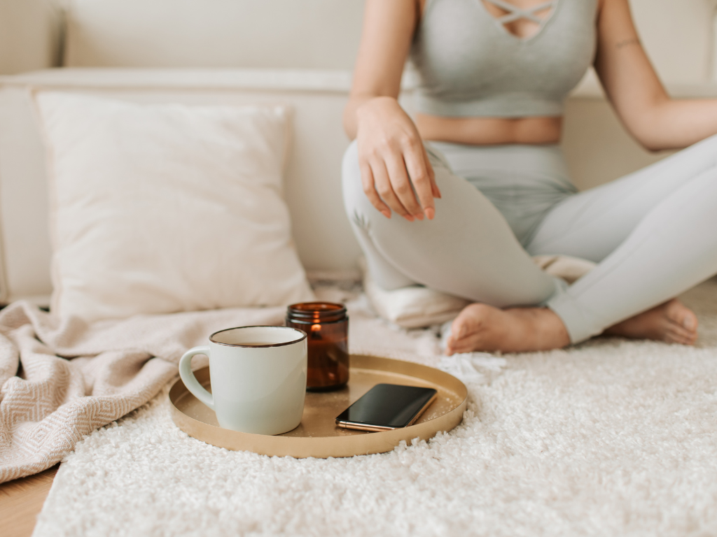 Cozy minimalist setting with a candle, phone, and coffee on a carpet—ideal scene to understand how candle wax might accidentally end up on rugs.