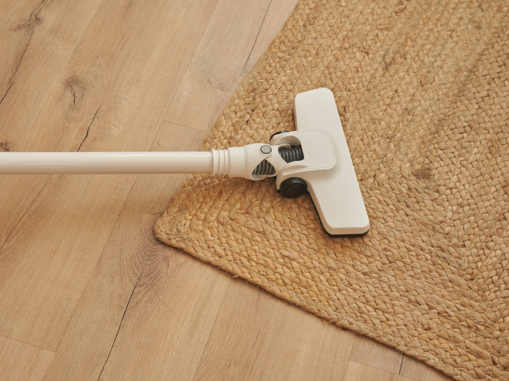 Vacuum head on a woven rug, illustrating the importance of removing wax particles from carpet after freezing or scraping off excess wax.