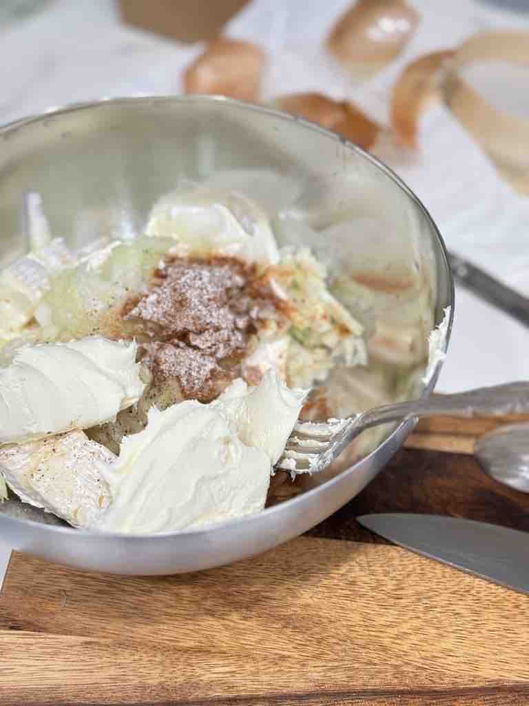 Mixing bowl filled with Camembert, cream cheese, onion, and spices before blending into German obatzda cheese dip.