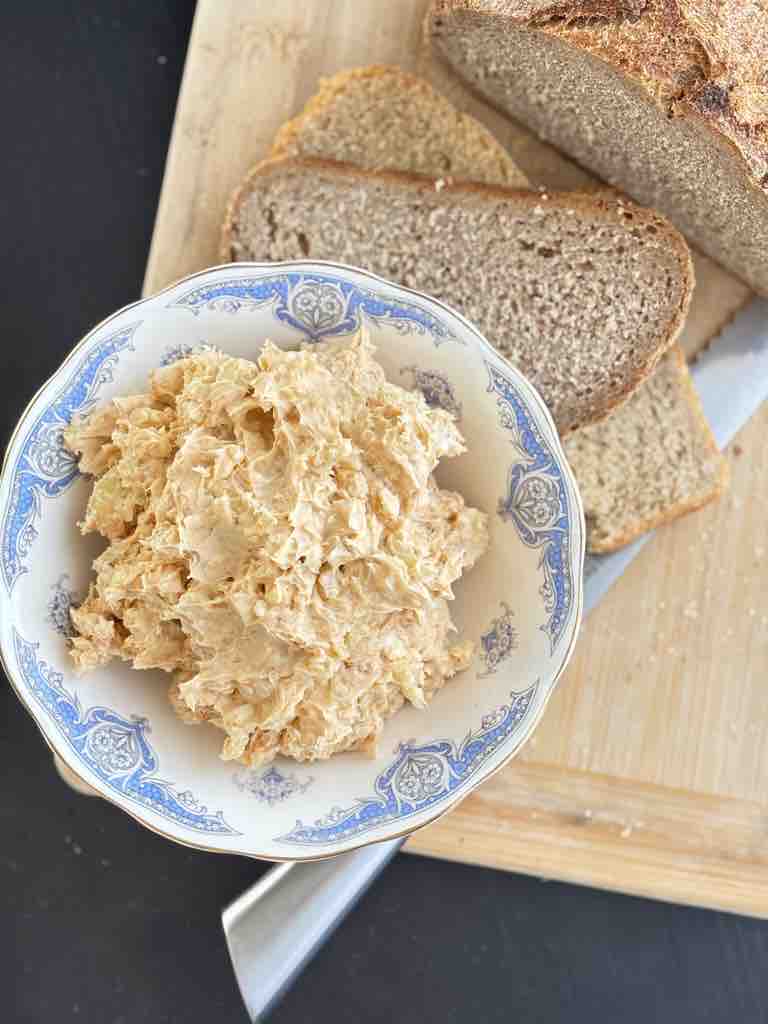 Top-down view of obatzda cheese dip and slices of crusty rye bread on a cutting board.