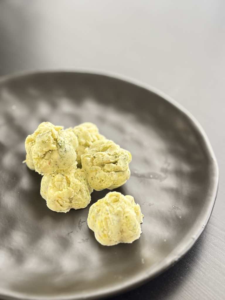 Rustic flower-shaped herb butter bites, frozen and ready to use, made from a traditional German-style herb butter recipe with dried herbs.
