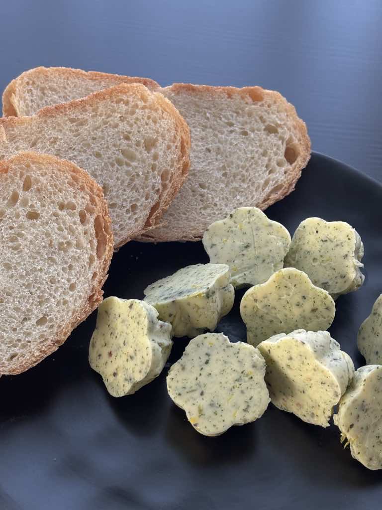A rustic serving plate with German bread and traditional herb butter made with dried herbs, shaped into charming flowers.