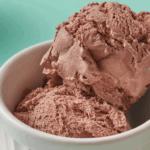 Creamy scoops of homemade chocolate ice cream recipe without eggs, served in a rustic white bowl.