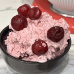 A generous scoop of homemade sour cherry ice cream served in a bowl and topped with whole sour cherries.