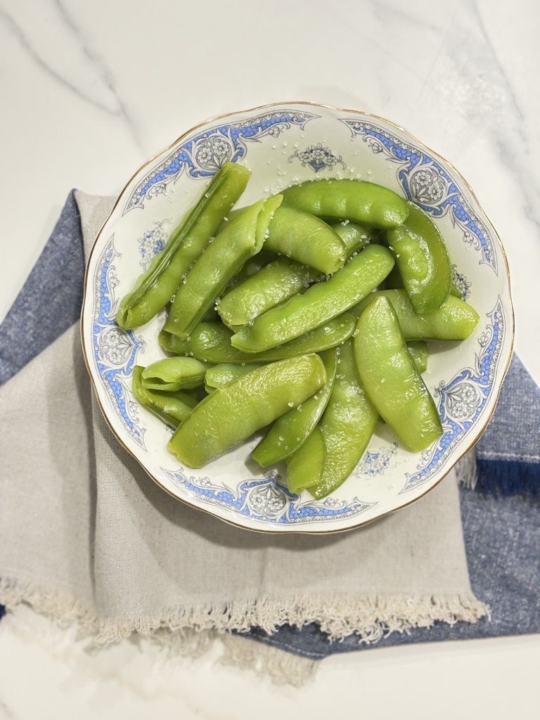 Steamed sugar snap peas with a sprinkle of sea salt in a vintage bowl. Perfect photo for how to steam sugar snap peas and season them naturally.