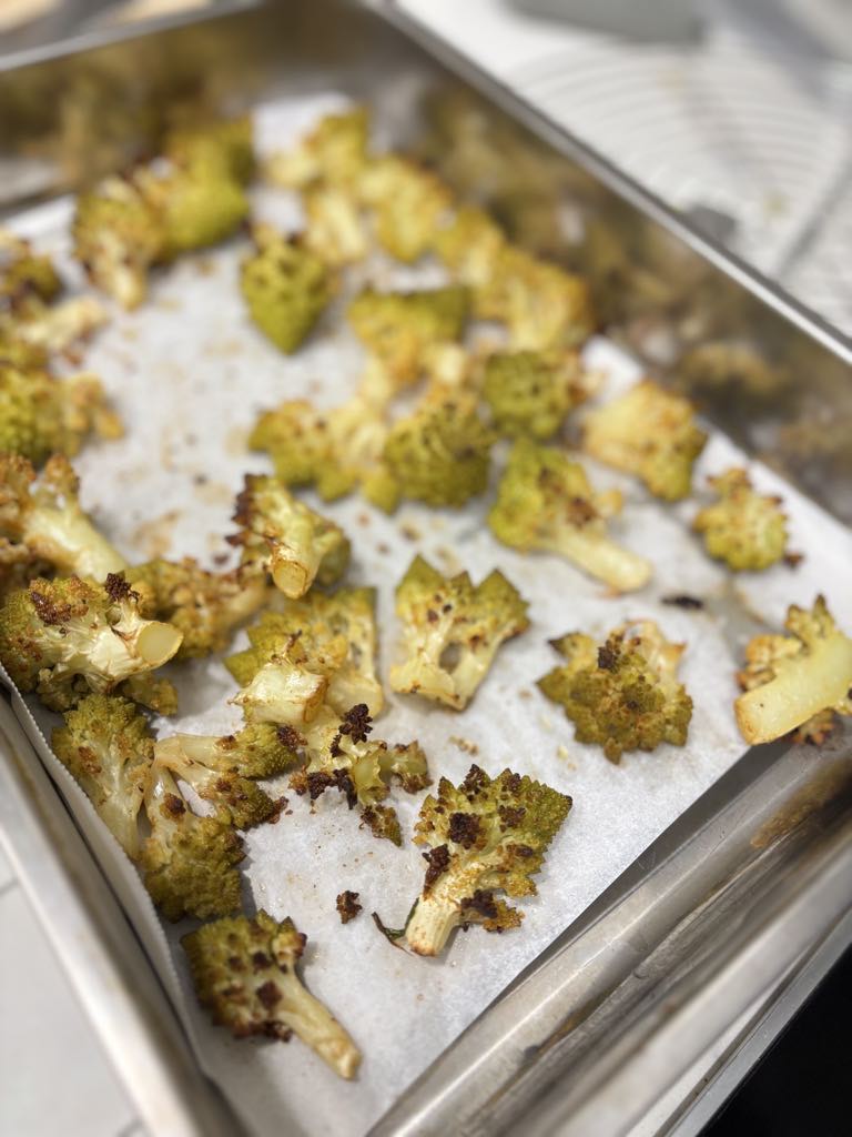 Crispy roasted green cauliflower florets fresh out of the oven, golden brown with caramelized edges, a delicious result of this easy green cauliflower recipe.