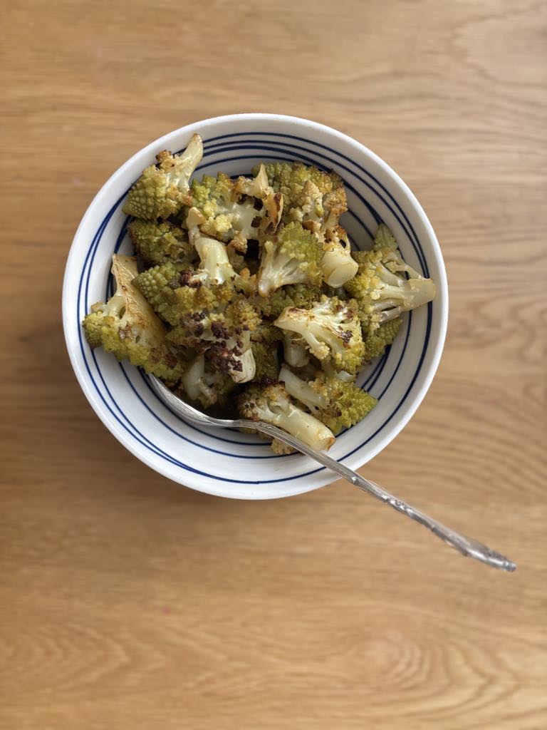 A serving bowl filled with roasted green cauliflower florets, a wholesome and rustic dish that’s perfect as a side or light vegetarian meal.