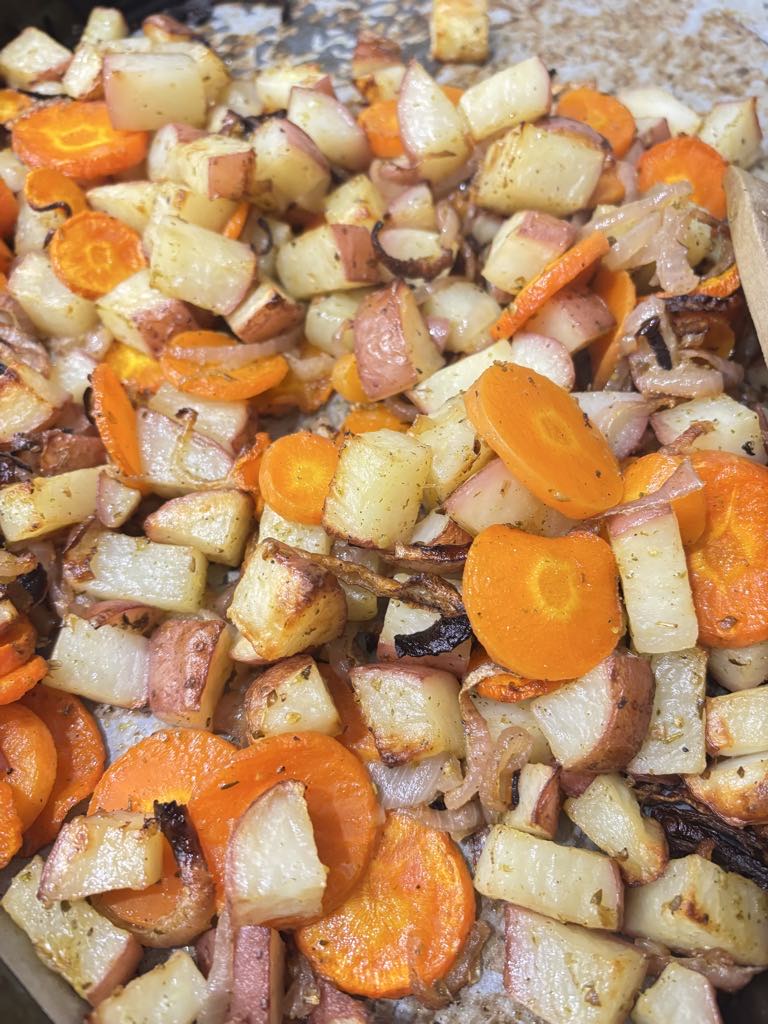 Golden roasted potatoes with caramelized onions and tender carrots on a sheet pan, perfect as a hearty rustic side or simple dinner.