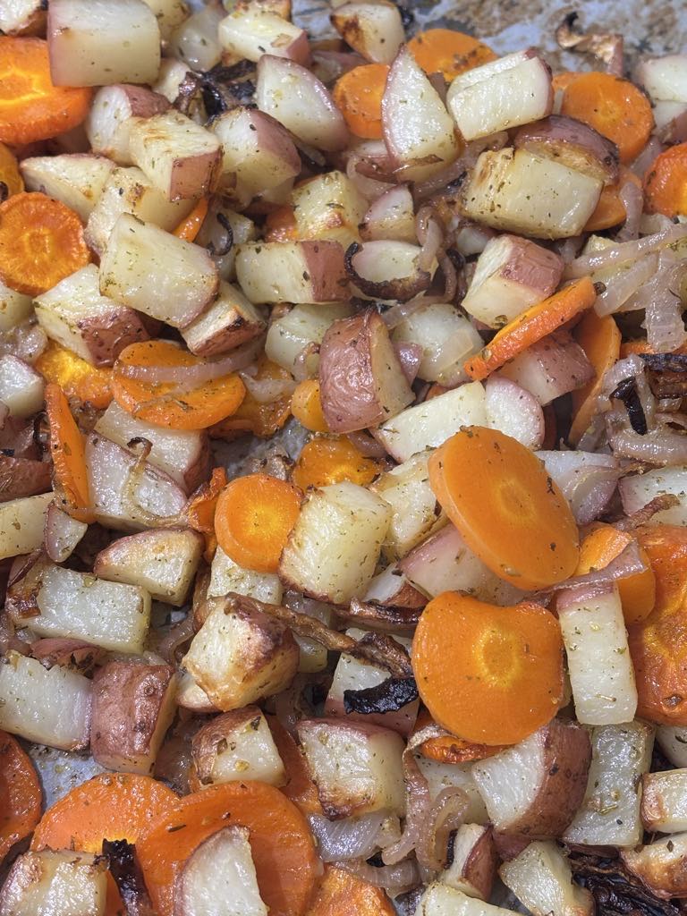 Close-up of a rustic tray bake showing perfectly roasted potato cubes, sweet onions, and carrot rounds for a cozy potato carrot onion sheet pan dinner.