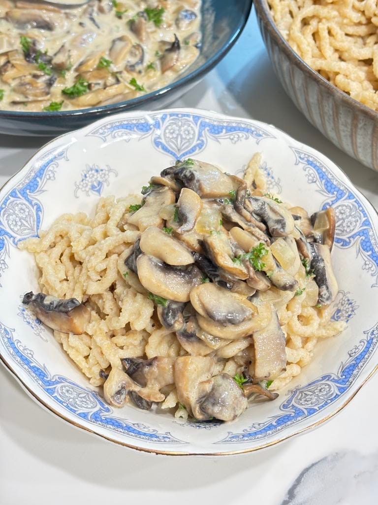 A plate of homemade German spaetzle topped with creamy mushroom sauce made with butter, cremini mushrooms, and heavy cream.