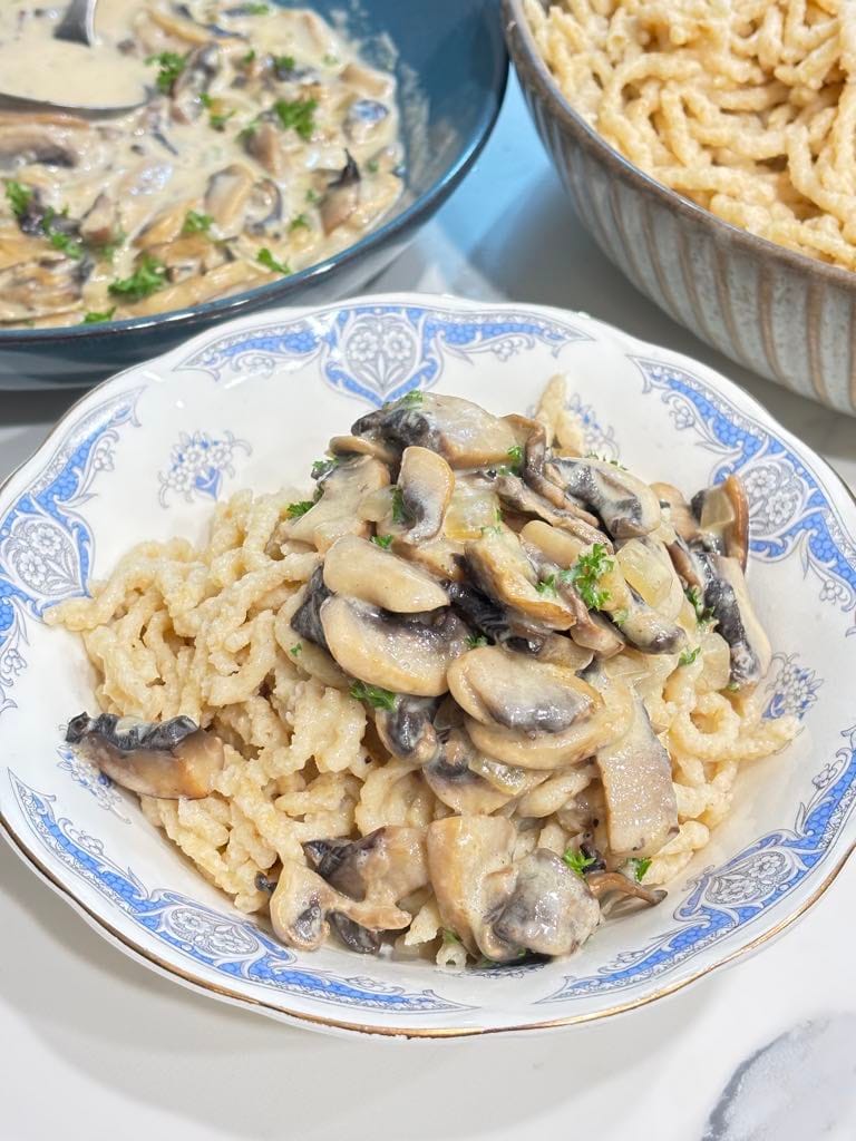 A traditional German comfort meal with soft spaetzle noodles generously topped with the best mushroom sauce, garnished with parsley.