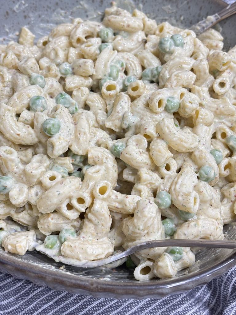 Elbow macaroni and peas tossed together with a thick homemade mayonnaise dressing, creating a rich and traditional macaroni salad.