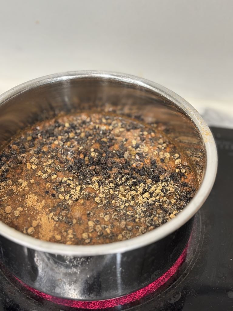 Black elderberries gently simmering in a pot of water as part of the slow, old-fashioned process of making homemade elderberry syrup.