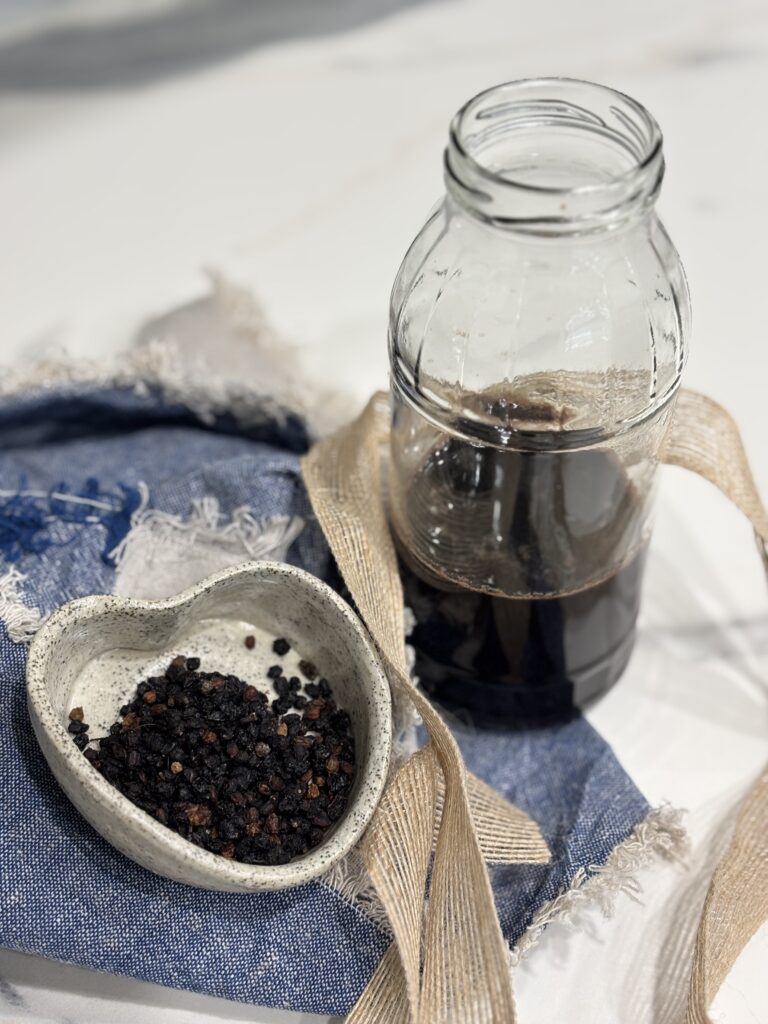 Homemade elderberry syrup styled on a linen cloth with dried berries, capturing a slow, old-school approach to natural remedies.